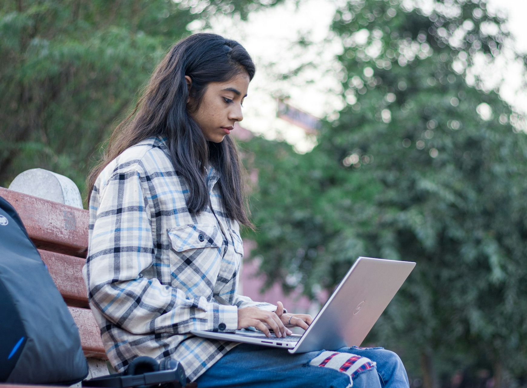 a woman sitting on a bench using a laptop computer